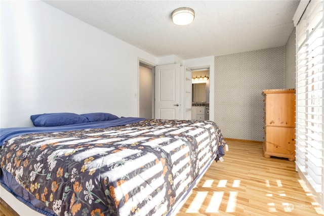 bedroom with ensuite bath and light hardwood / wood-style floors