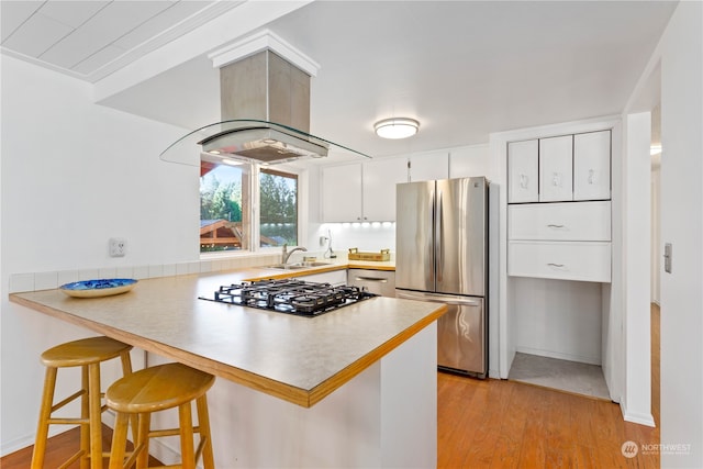 kitchen featuring appliances with stainless steel finishes, a breakfast bar area, kitchen peninsula, light hardwood / wood-style flooring, and white cabinets