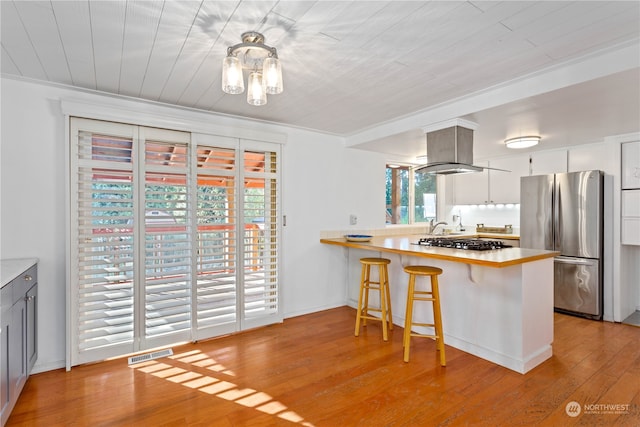 kitchen featuring appliances with stainless steel finishes, light hardwood / wood-style flooring, white cabinetry, and crown molding