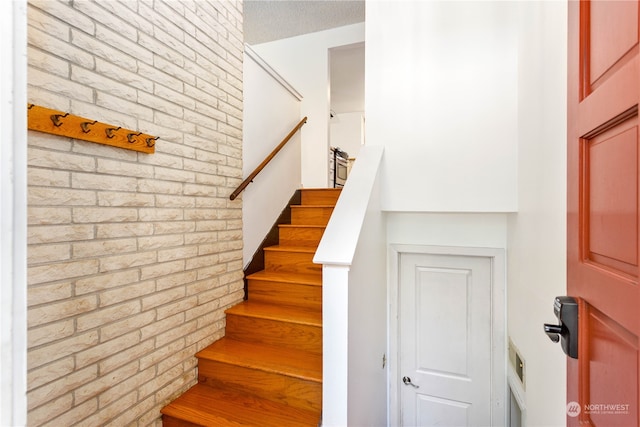 stairway featuring brick wall