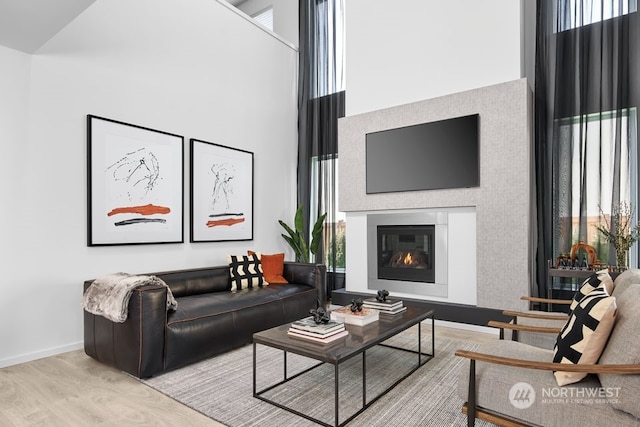 living room featuring a towering ceiling, light hardwood / wood-style floors, and a wealth of natural light