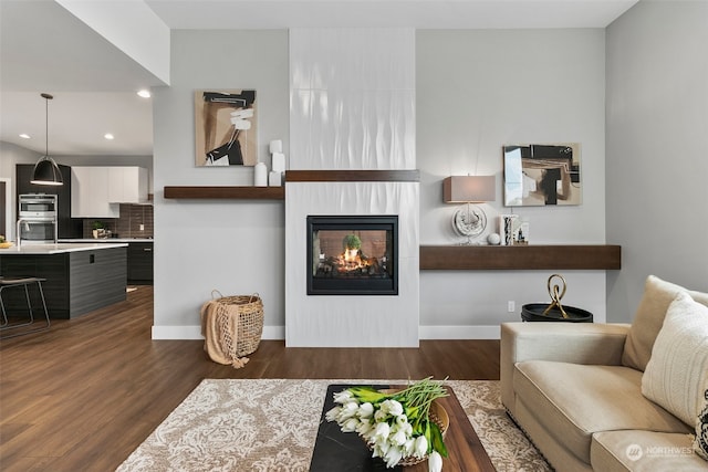 living room with a multi sided fireplace and dark wood-type flooring