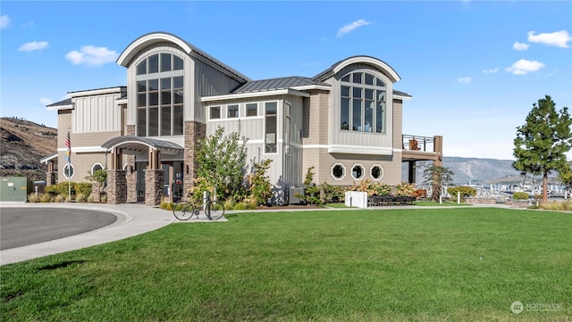 view of front of house featuring a balcony, a front lawn, and a mountain view