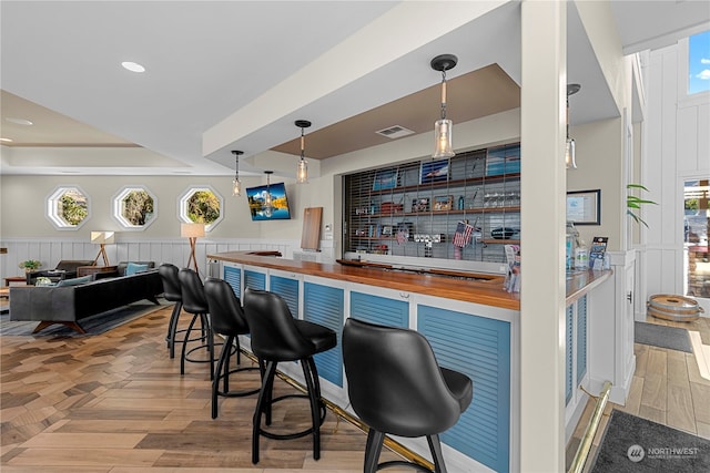 bar with wooden counters, pendant lighting, and plenty of natural light