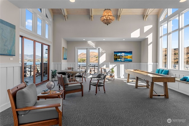 interior space featuring beam ceiling, dark colored carpet, a chandelier, and a wealth of natural light