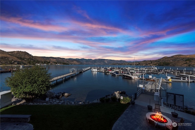 water view with a fire pit, a mountain view, and a dock