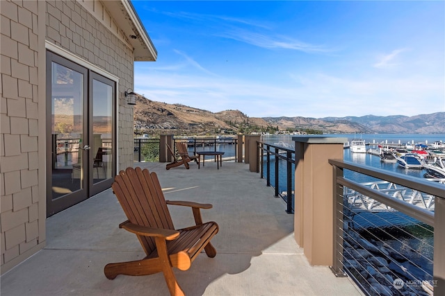 balcony with a water and mountain view and french doors