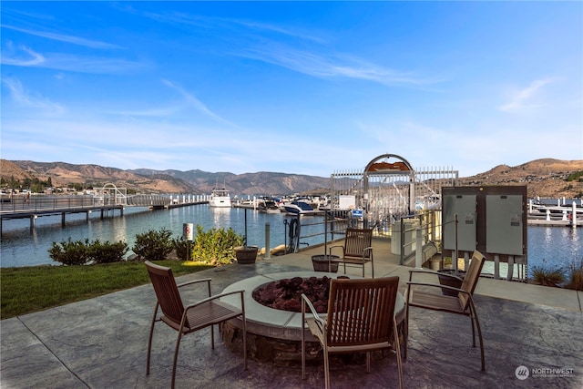 view of terrace with a water and mountain view and a dock