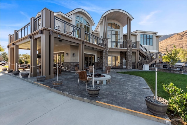 view of front facade featuring a fire pit, central air condition unit, a front yard, a patio, and a balcony