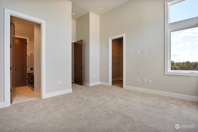 unfurnished bedroom featuring a walk in closet, light carpet, and a closet