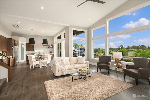 living room featuring dark hardwood / wood-style flooring, ceiling fan, and a high ceiling