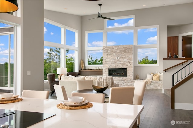 dining space with a towering ceiling, ceiling fan, dark hardwood / wood-style floors, and a fireplace