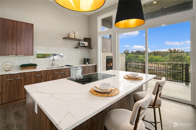 kitchen featuring a center island, black electric stovetop, backsplash, light wood-type flooring, and sink