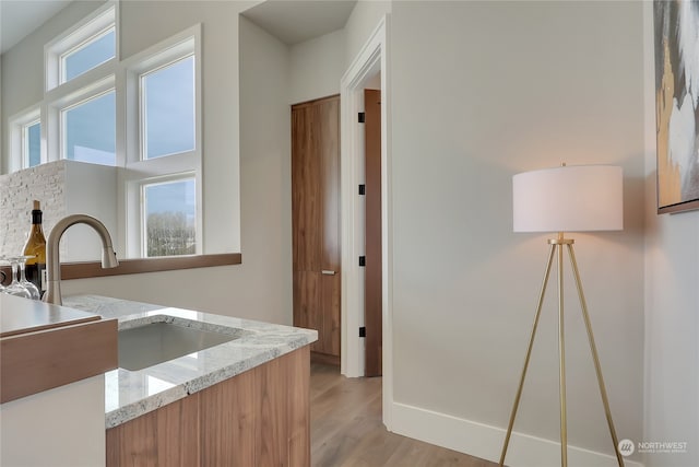 interior space with light stone countertops, light hardwood / wood-style flooring, and sink