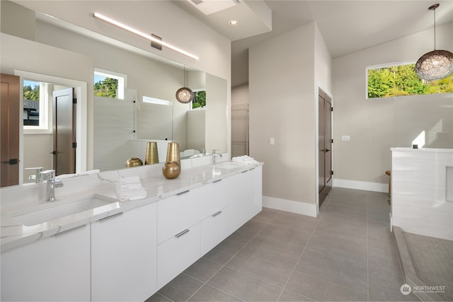 bathroom featuring double sink, tile floors, a wealth of natural light, and vanity with extensive cabinet space