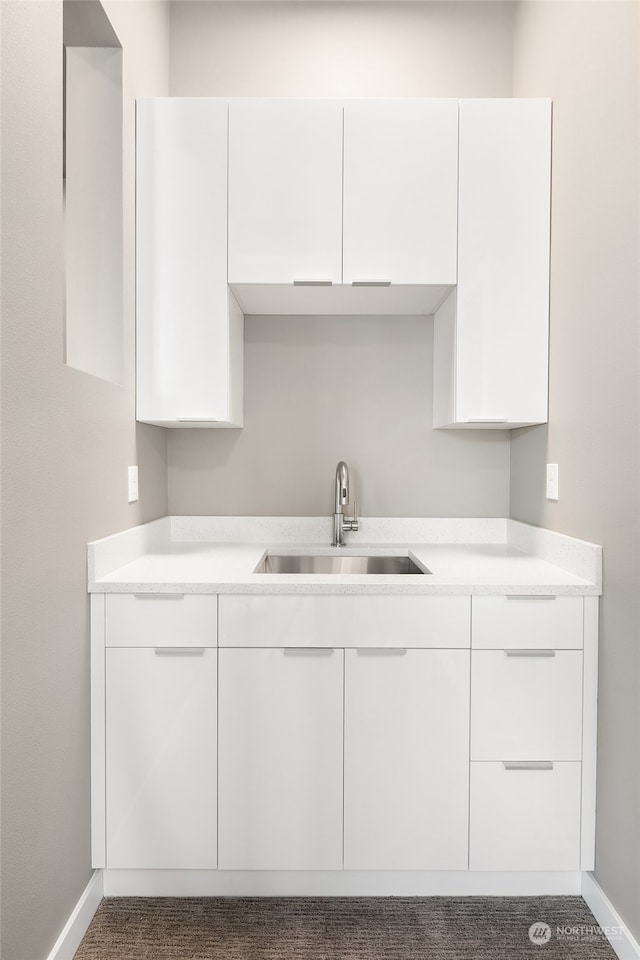 kitchen with white cabinets, carpet floors, and sink