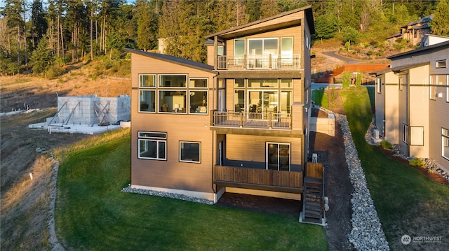 rear view of house featuring a balcony and a lawn