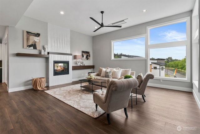 living room featuring a multi sided fireplace, wood-type flooring, and ceiling fan