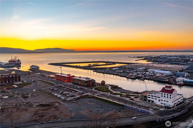 aerial view at dusk featuring a water and mountain view