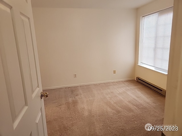 carpeted empty room with a baseboard heating unit