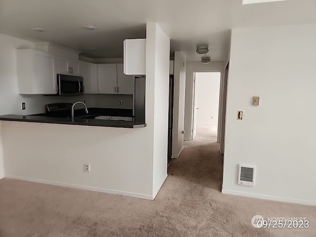 kitchen with white cabinets, sink, and light colored carpet