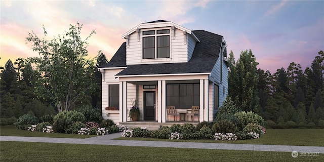 view of front of home featuring covered porch, a shingled roof, and a front lawn