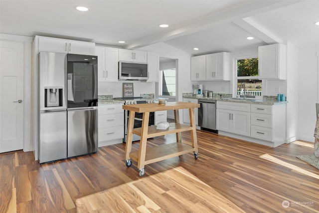 kitchen featuring hardwood / wood-style floors, stainless steel appliances, white cabinetry, and light stone counters