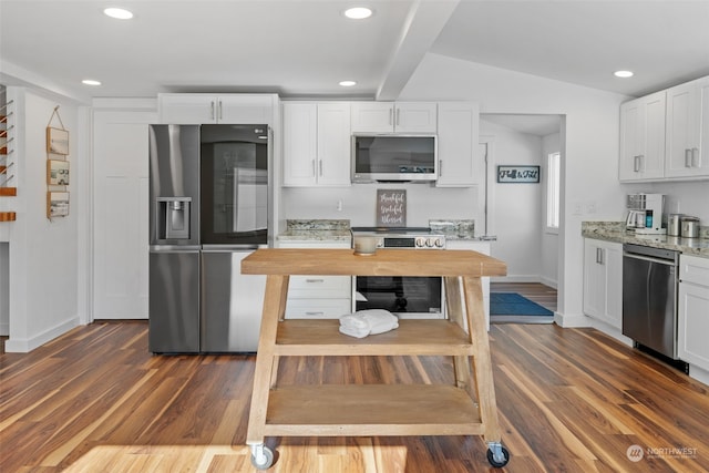 kitchen featuring light stone counters, appliances with stainless steel finishes, lofted ceiling with beams, dark wood-type flooring, and white cabinetry