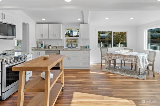 kitchen with white cabinets, light wood-type flooring, and appliances with stainless steel finishes