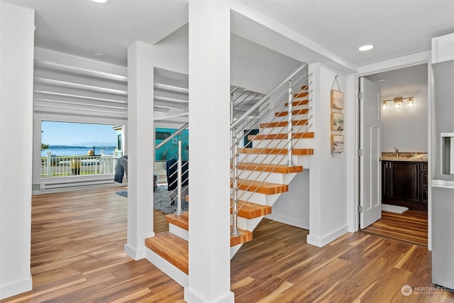 staircase featuring wood-type flooring and sink