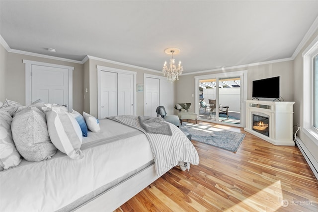 bedroom featuring a notable chandelier, access to exterior, multiple closets, ornamental molding, and light hardwood / wood-style flooring