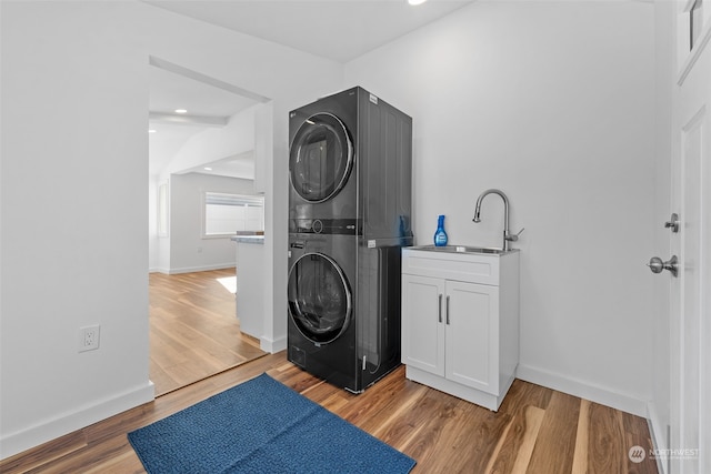 washroom featuring sink, light hardwood / wood-style floors, cabinets, and stacked washer and dryer