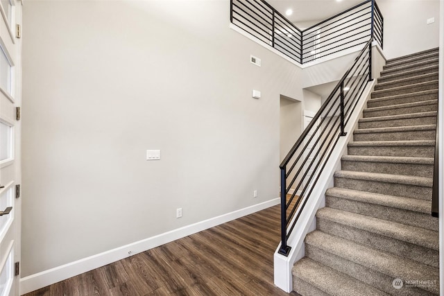 stairway featuring wood-type flooring and a towering ceiling