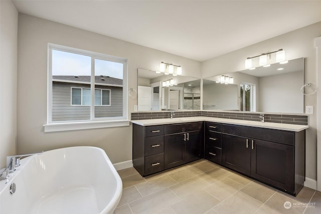 bathroom with tile patterned floors, vanity, a tub, and a wealth of natural light