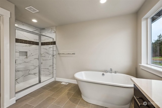 bathroom with vanity and shower with separate bathtub