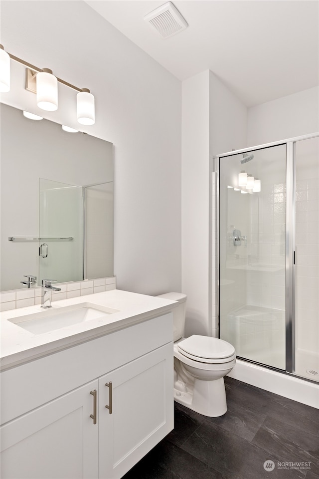 bathroom featuring vanity, a shower with shower door, and toilet