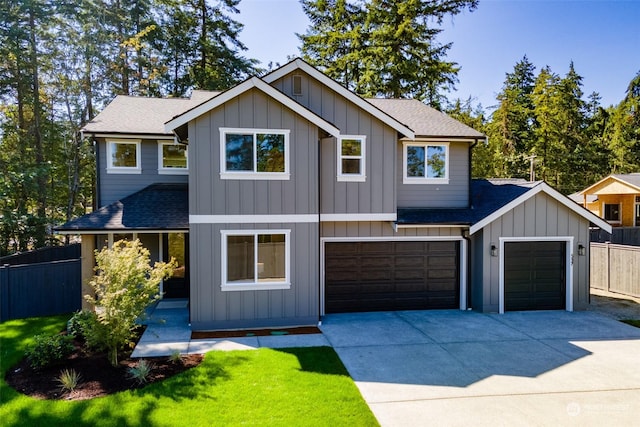 view of front of house with board and batten siding, concrete driveway, roof with shingles, and fence