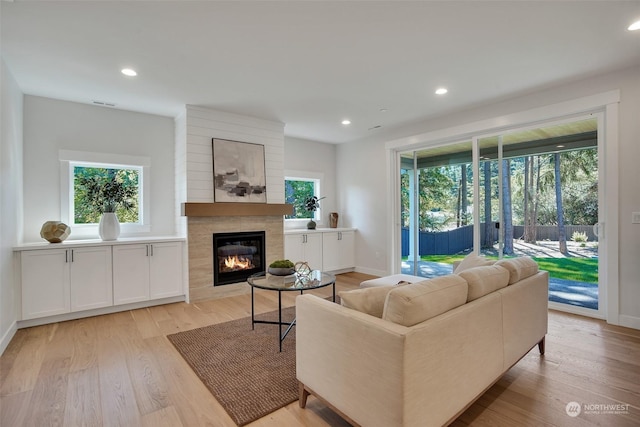 living area with recessed lighting, light wood-type flooring, a fireplace, and a healthy amount of sunlight