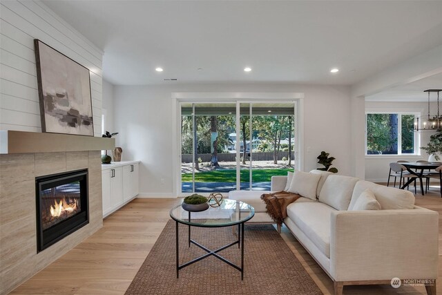 living room with plenty of natural light, a fireplace, light hardwood / wood-style flooring, and a notable chandelier