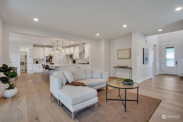 living room with recessed lighting, light wood-style flooring, and baseboards