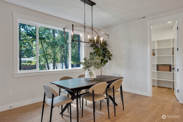 dining space featuring light hardwood / wood-style floors, a wealth of natural light, and a chandelier