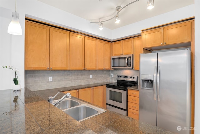 kitchen with appliances with stainless steel finishes, tasteful backsplash, decorative light fixtures, sink, and rail lighting