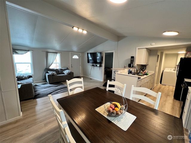 dining room with light wood-type flooring, washer / clothes dryer, and lofted ceiling with beams