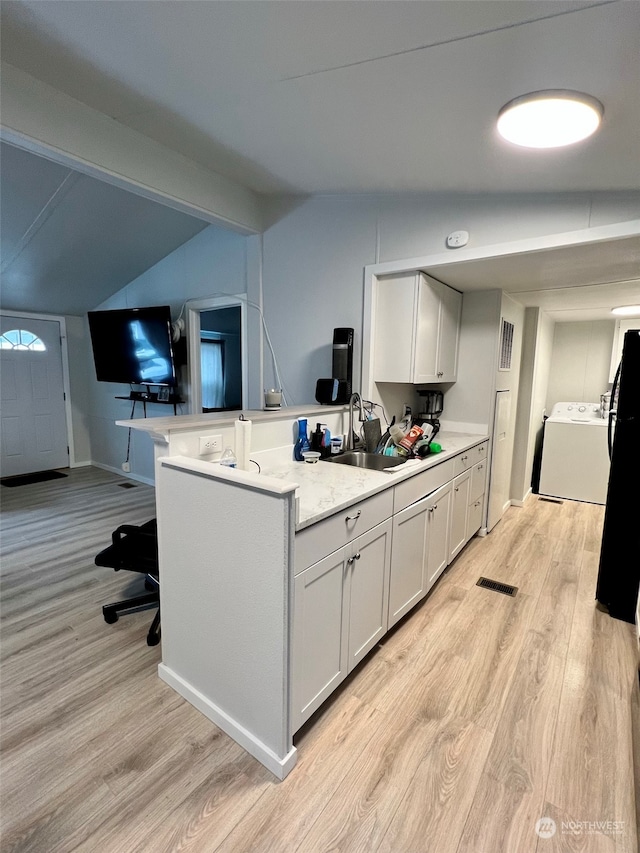 kitchen with light wood finished floors, washer / clothes dryer, lofted ceiling with beams, and a sink