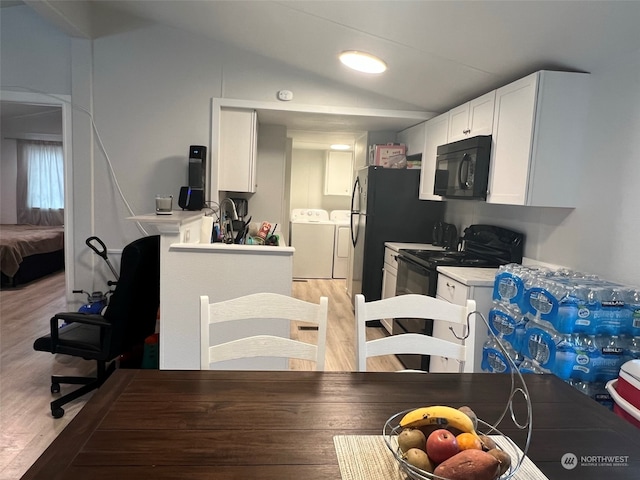 kitchen featuring black appliances, vaulted ceiling, light wood finished floors, and washing machine and clothes dryer