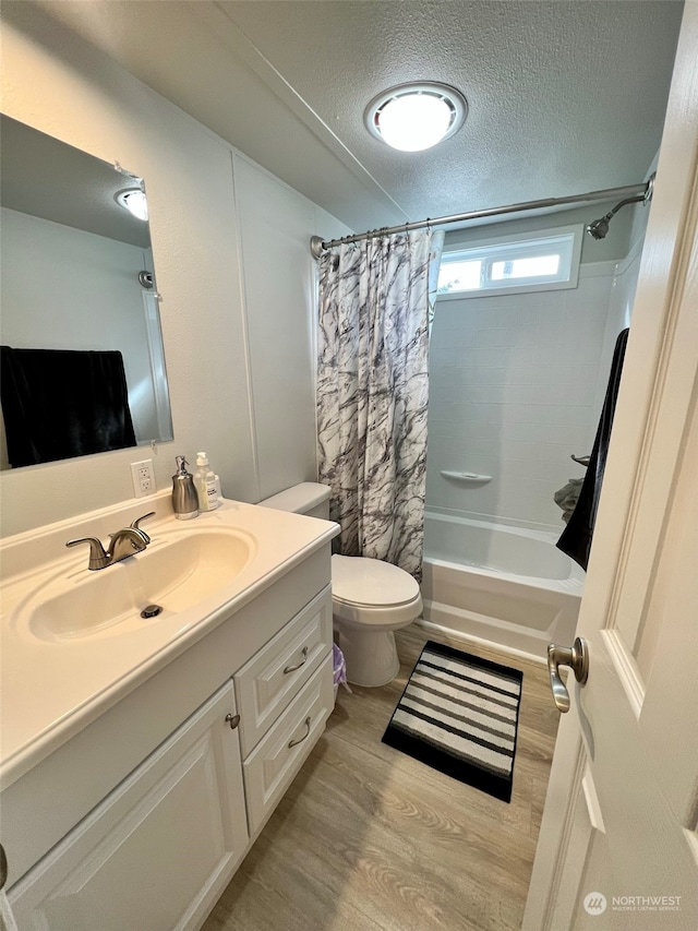 full bathroom featuring toilet, shower / bath combo, a textured ceiling, wood finished floors, and vanity