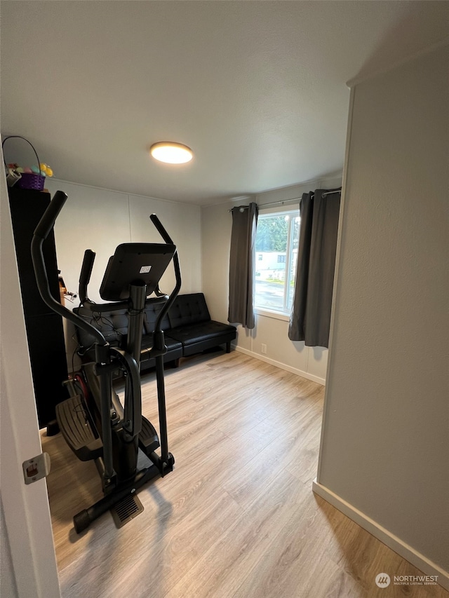 workout area featuring light wood-type flooring and baseboards