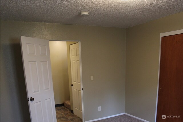 spare room featuring dark tile floors and a textured ceiling