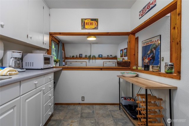 kitchen with white cabinetry and dark tile flooring