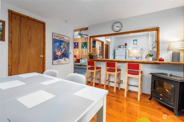 dining space featuring ceiling fan, a wood stove, and light hardwood / wood-style flooring